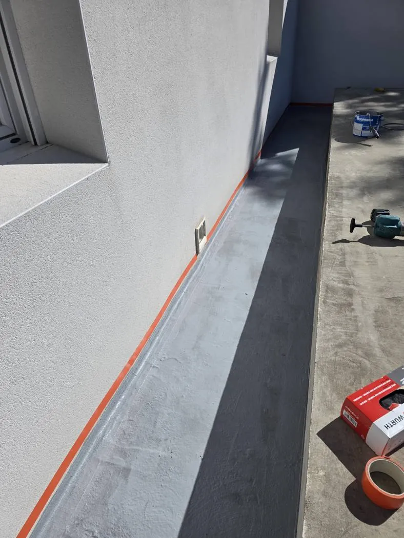 Relevé d'étanchéité traité à la résine Alsan Flashing (Soprema) le long d'un mur – chantier Occi'Dry Services