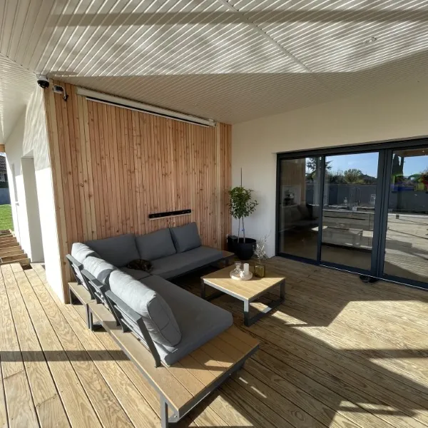 Bardage bois clair sur une terrasse couverte et la façade d'une maison